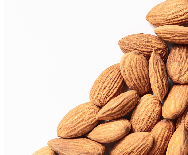 Close-up of whole almonds showing textured brown skins on a white background